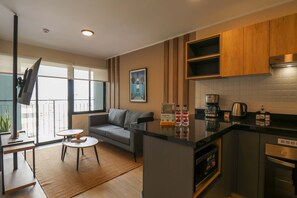 A modern kitchen with a built-in island, a dining area with a sofa and coffee table, and a large window providing natural light. - w Charming Loft w Balcony in Prime Miraflores (Lima)