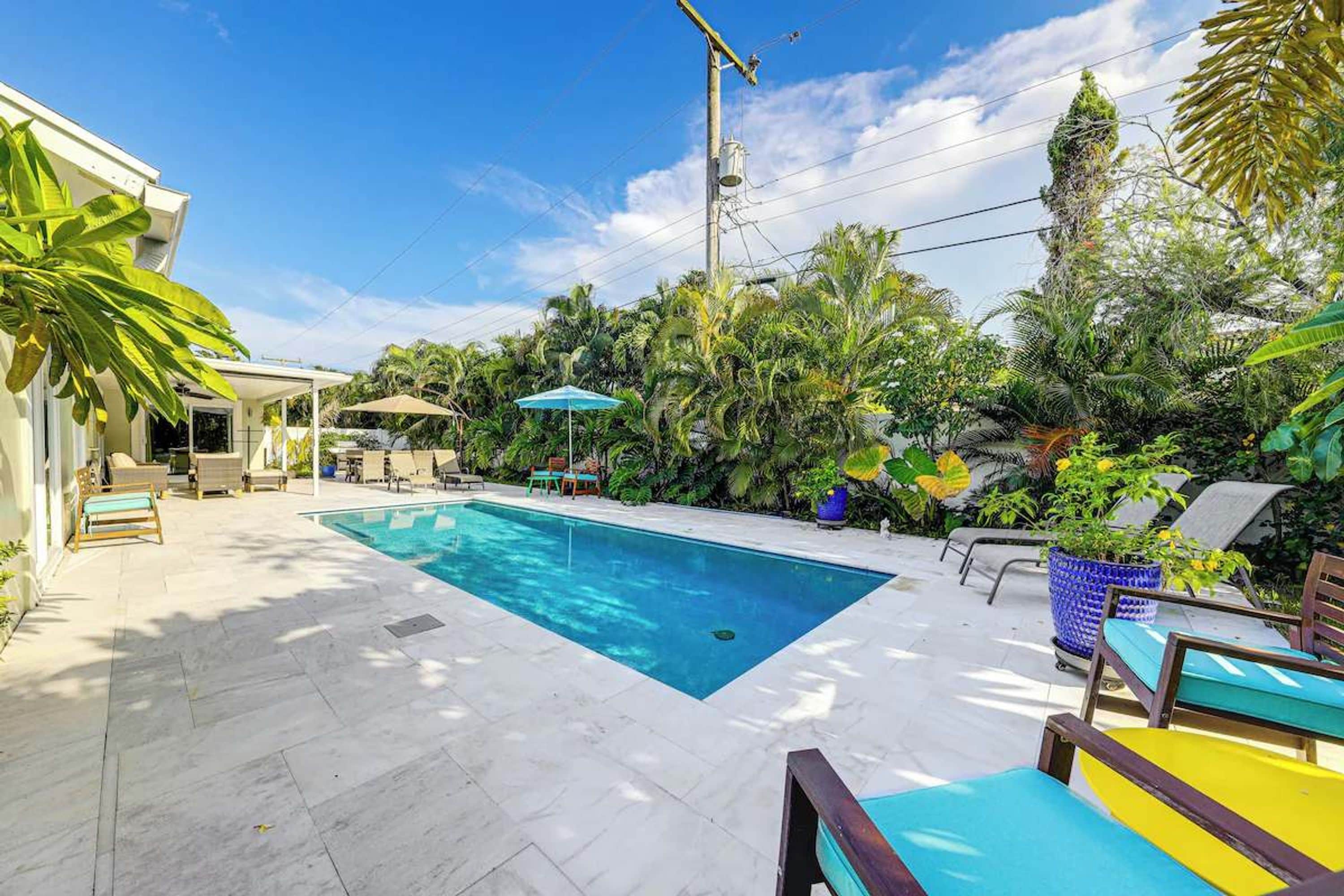 A swimming pool with lounge chairs and umbrellas, surrounded by tropical plants.