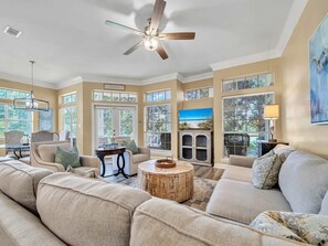 A spacious living room with a large sofa, a coffee table, and a ceiling fan. - Golf Course View Villa With Luxury 6 Seater Golf Cart Steps to Beach Pool Tram Just Across From Entry (Miramar Beach)
