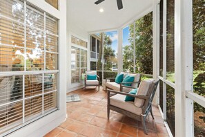 A covered patio area with a seating arrangement, including a sofa and chairs, and a welcome mat. - Golf Course View Villa With Luxury 6 Seater Golf Cart Steps to Beach Pool Tram Just Across From Entry (Miramar Beach)