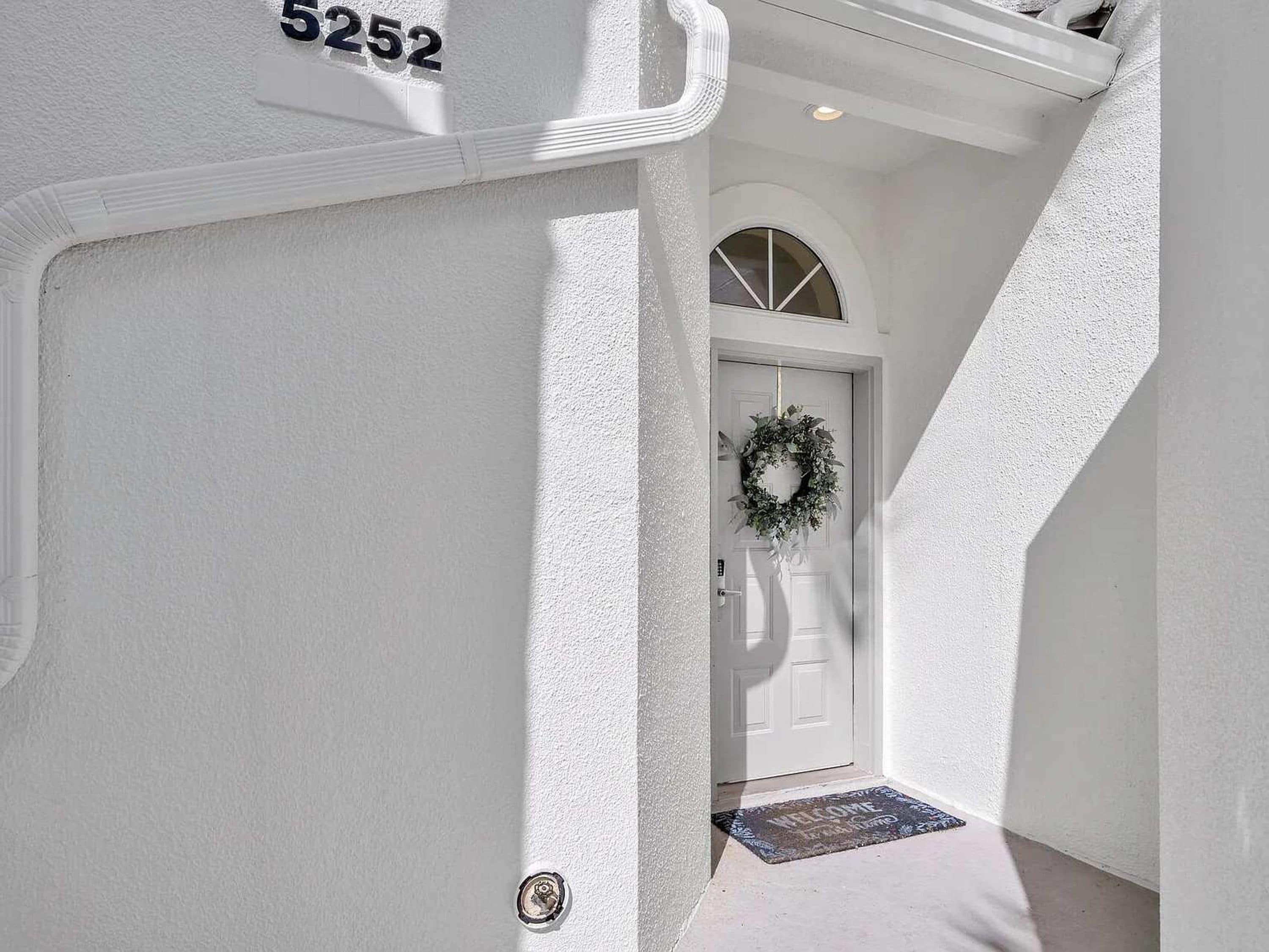 A white exterior wall with a number plaque '5252' and a door with a wreath.