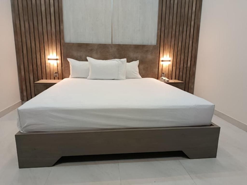 A modern bedroom with a large bed, wooden headboard, and bedside lamps.