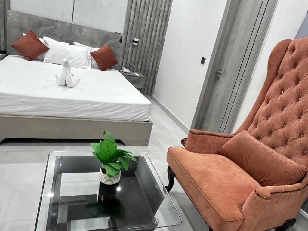 A modern bedroom with a bed, a tufted armchair, and a glass coffee table with a plant.