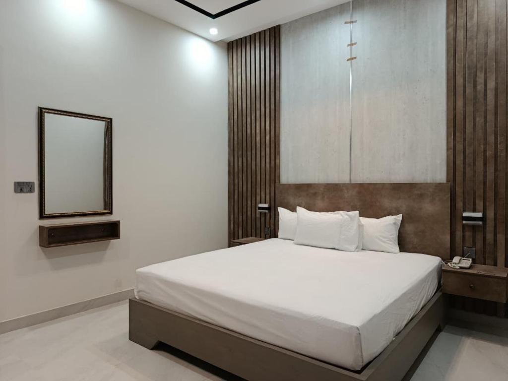 Une chambre à coucher moderne avec un grand lit, une table de chevet avec un téléphone et un miroir fixé au mur.