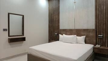 Une chambre à coucher moderne avec un grand lit, une table de chevet avec un téléphone et un miroir fixé au mur.