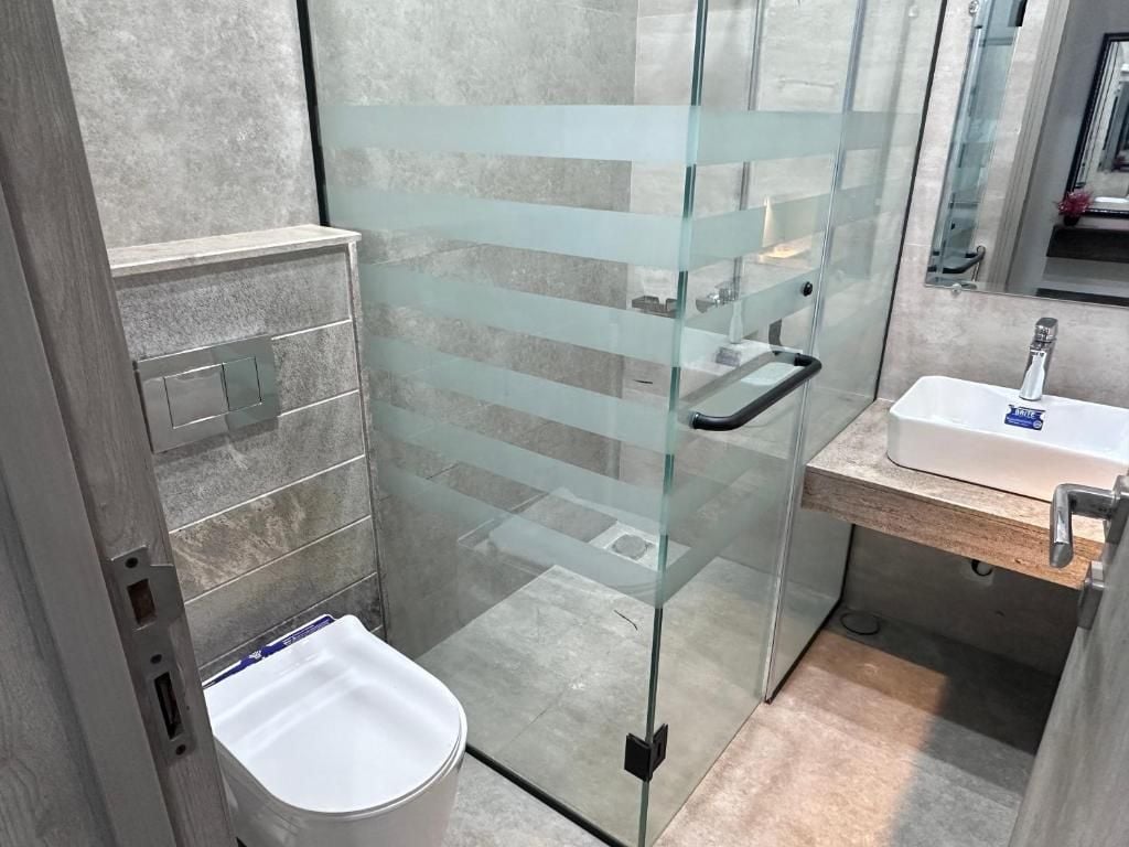 A modern bathroom with a glass shower enclosure, a white sink, and a wooden vanity.