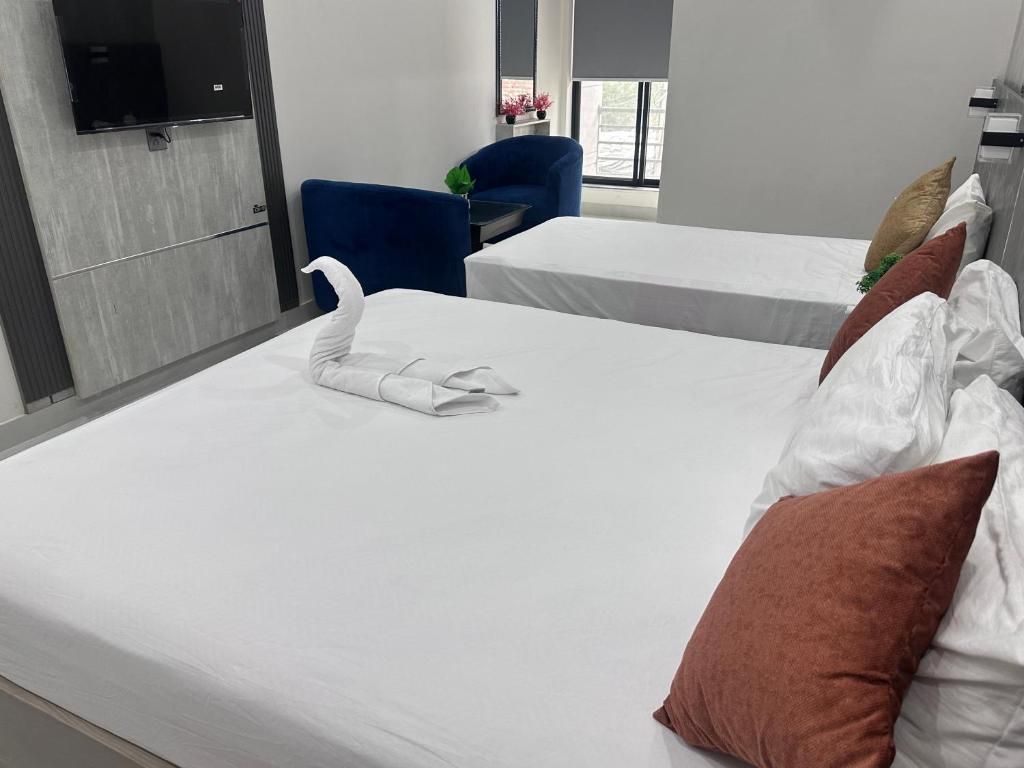 Une chambre d’hôtel avec deux lits, un téléviseur à écran plat fixé au mur, un fauteuil bleu et une fenêtre donnant sur un paysage agréable.