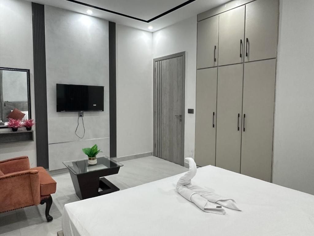 Un dormitorio moderno con cama, televisión, armario y zona de estar.