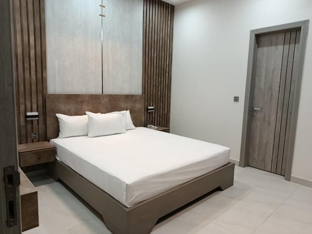 A bedroom with a large bed, wooden headboard, bedside tables, and a wardrobe.