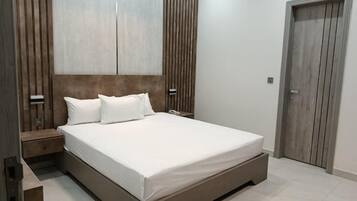 A bedroom with a large bed, wooden headboard, bedside tables, and a wardrobe.