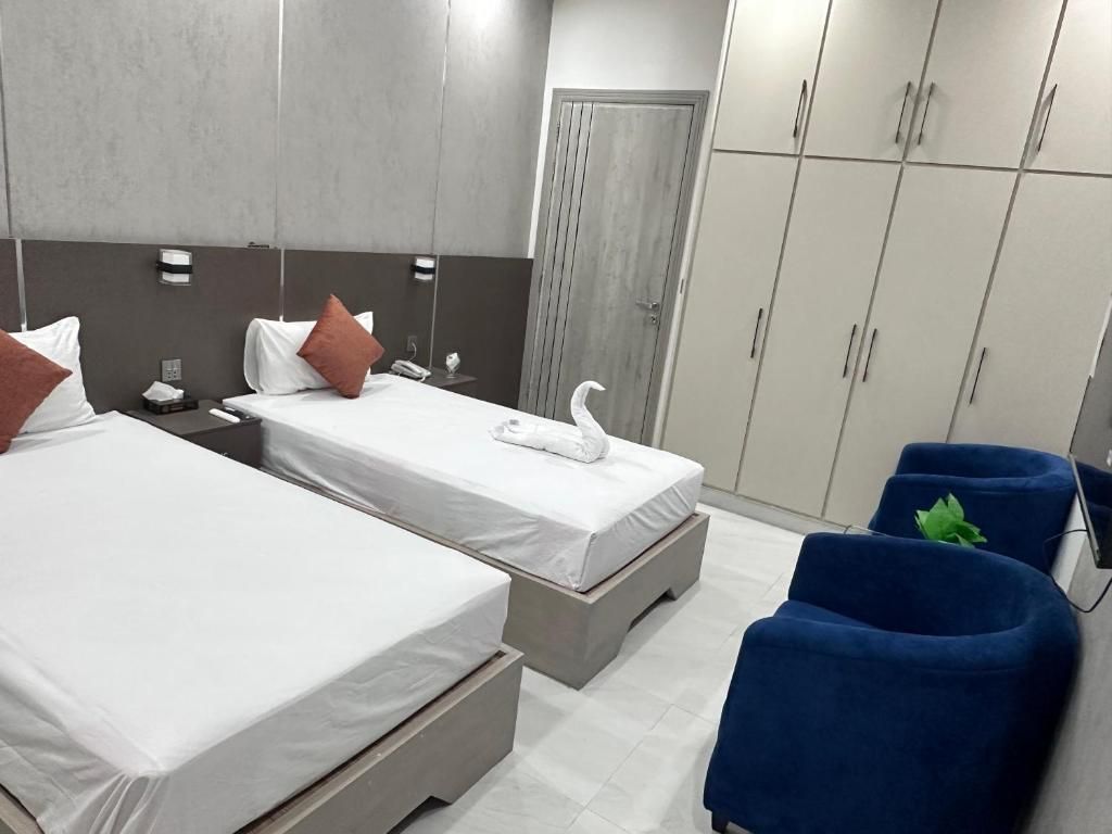 A hotel room with two beds, a wardrobe, and a seating area.