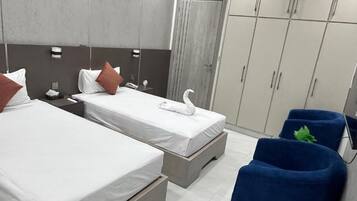 Habitación de hotel con dos camas, un armario y una zona de estar.