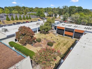 A parking lot with multiple cars, a building with a flat roof, and a landscaped area with trees and shrubs. - Sleek apt near The Grand Ole Opry and BNA Airport! (Nashville)
