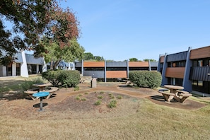 A courtyard with outdoor seating, a tree, and modern buildings with large windows. - Sleek apt near The Grand Ole Opry and BNA Airport! (Nashville)