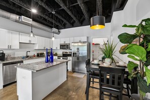 Una cocina moderna con gabinetes blancos, electrodomésticos de acero inoxidable y una isla central.