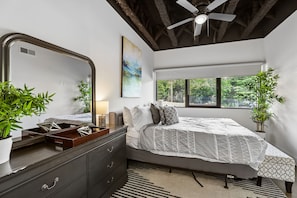 A bedroom with a bed, dresser, mirror, ceiling fan, window, and two potted plants. - Sleek apt near The Grand Ole Opry and BNA Airport! (Nashville)
