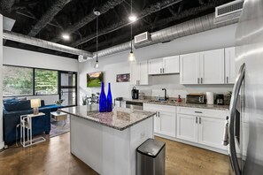 Una cocina moderna con armarios blancos, encimera de granito y electrodomésticos de acero inoxidable.