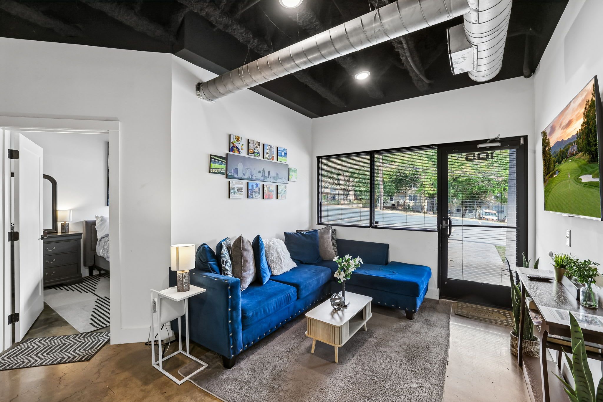 A modern living room with a blue sofa, a coffee table, and a large window with blinds.