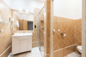 Ein Badezimmer mit Dusche, Toilette, Waschbecken und Spiegel.