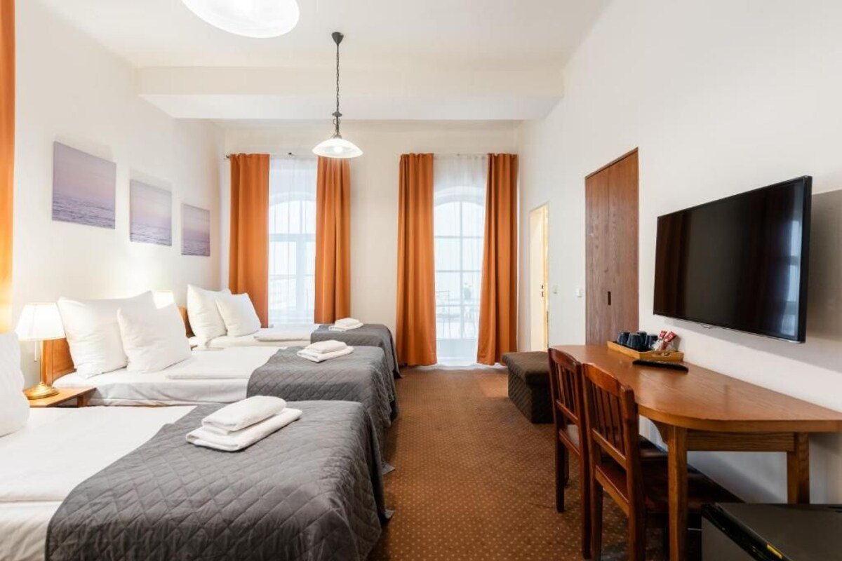 Ein Hotelzimmer mit zwei Betten, einem Schreibtisch, einem Fernseher und Blick auf die Stadt.