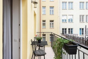 Ein Balkon mit Tisch, Stühlen und einem Blumentopf, sowie einem Geländer.