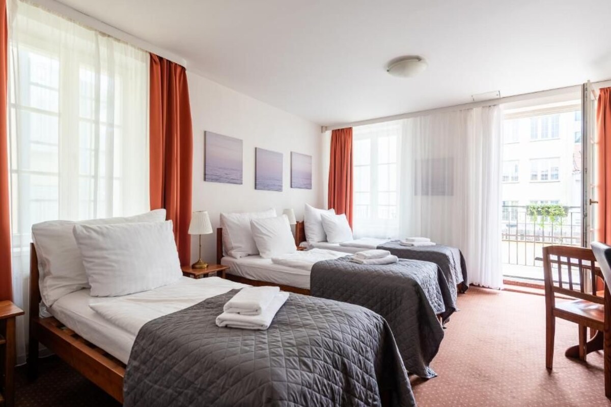 Ein Hotelzimmer mit zwei Betten, einem Sessel und Blick auf die Stadt.