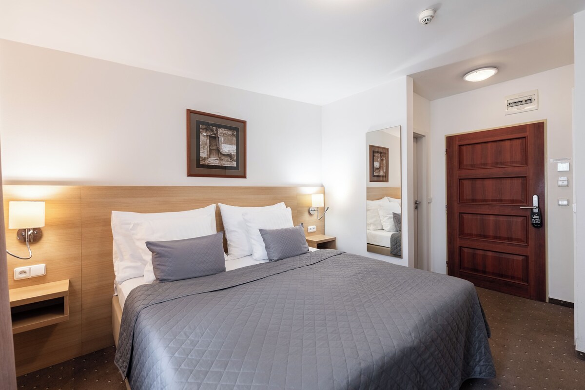 Ein Hotelzimmer mit Bett, Nachttischlampen, einer Tür und einer Wandleuchte.