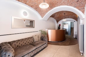 Ein modernes Interieur mit einer рароtierten Couch, einem Empfangsbereich und einer Ziegeldecke.