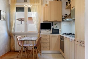Une cuisine compacte avec des meubles en bois, une table à manger avec des chaises, un four à micro-ondes et une cuisinière.
