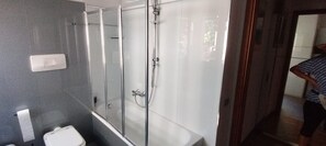 Ein Badezimmer mit Duschkabine aus Glas, Toilette und Waschbecken.