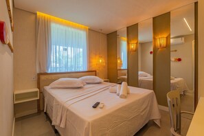 Une chambre d’hôtel avec un lit, une table de chevet, un miroir et une fenêtre avec des rideaux.