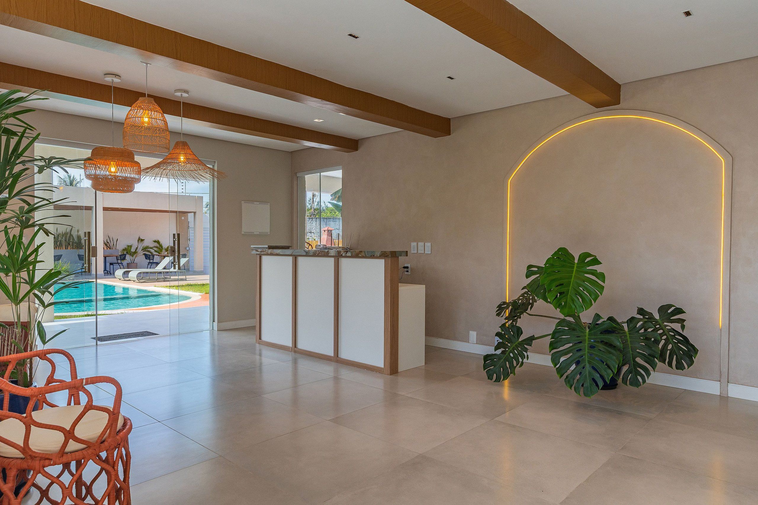 A modern reception area with a pool view, a reception desk, and tropical plants.