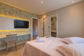 A hotel room with a bed, a chair, a television mounted on the wall, and a door leading to a bathroom. - Villa Pilar Cumbuco House With Pool by Carpediem (Caucaia)