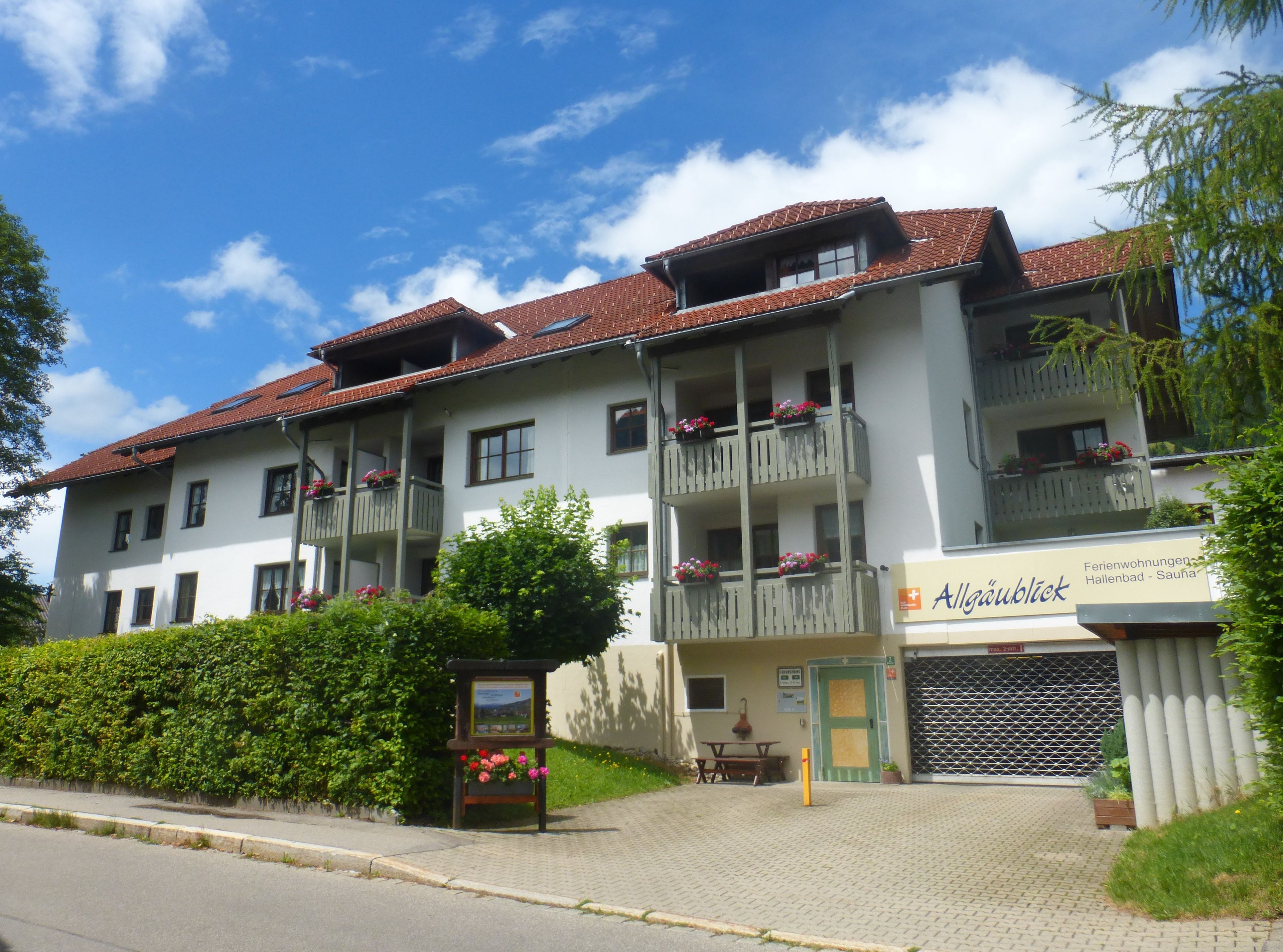 A multi-story hotel with balconies, a signboard, and a paved entrance.