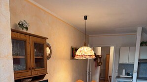 Una cucina compatta con zona pranzo, mobili in legno, una televisione e un frigorifero.