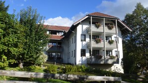 Un edificio a due piani con balconi, immerso nel verde.