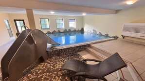 Una piscina interna con bordo in pietra, uno scivolo e una poltrona da relax.
