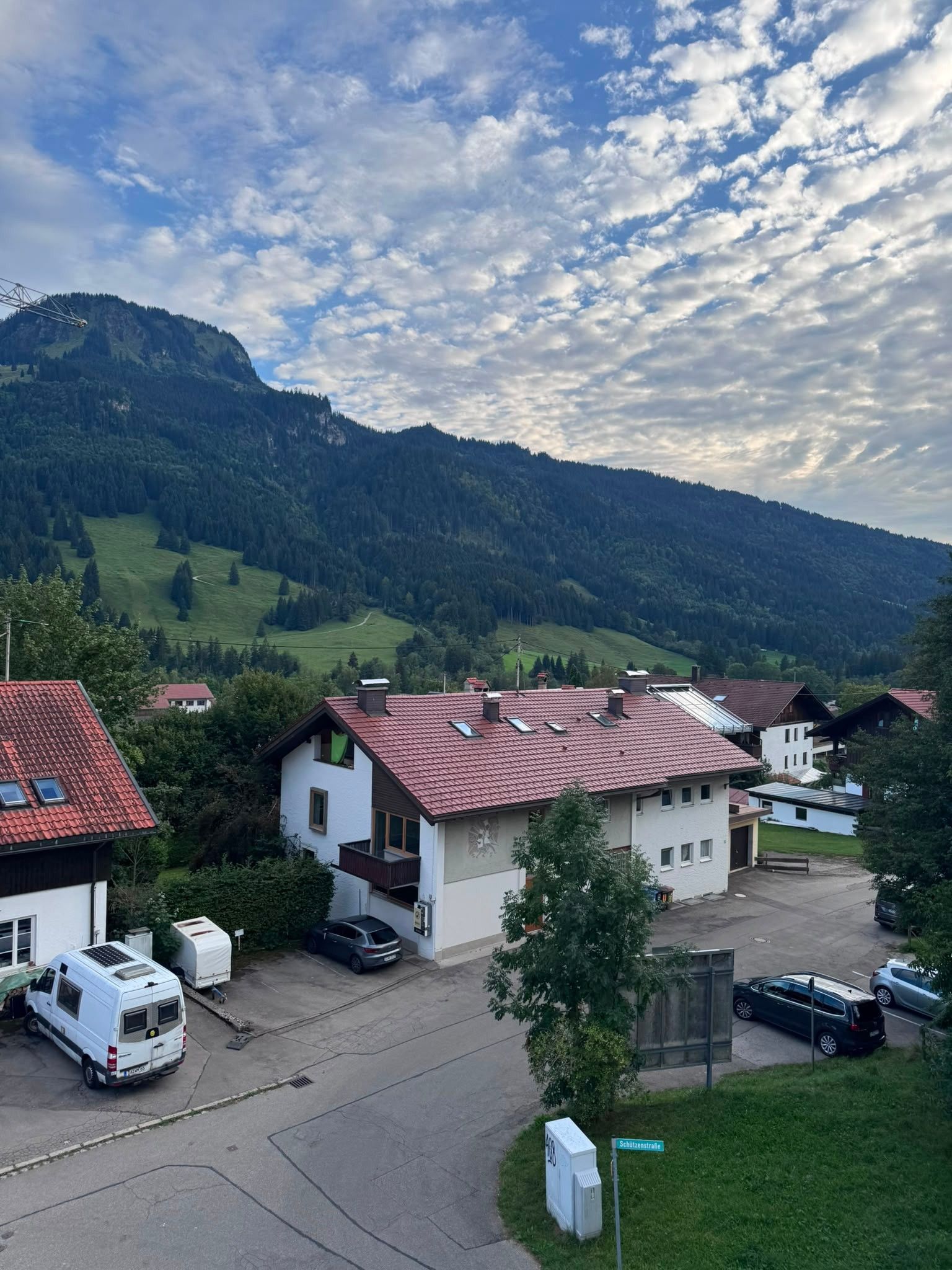 A residential area with houses, a parking lot, and a mountainous backdrop.