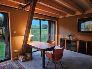 Une pièce comprenant une table à manger, des chaises, une lampe, une cheminée et une vue sur l’extérieur.