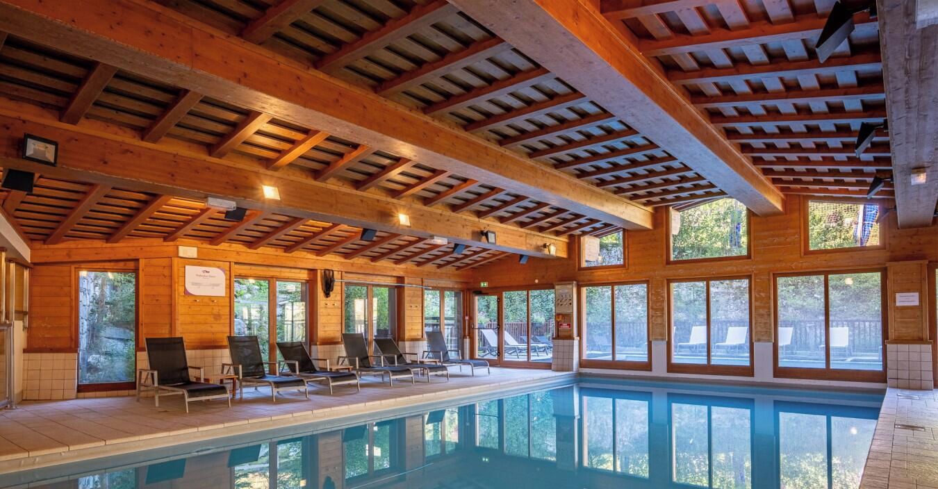 Ein Hallenbad mit Holzbalken und großen Fenstern.