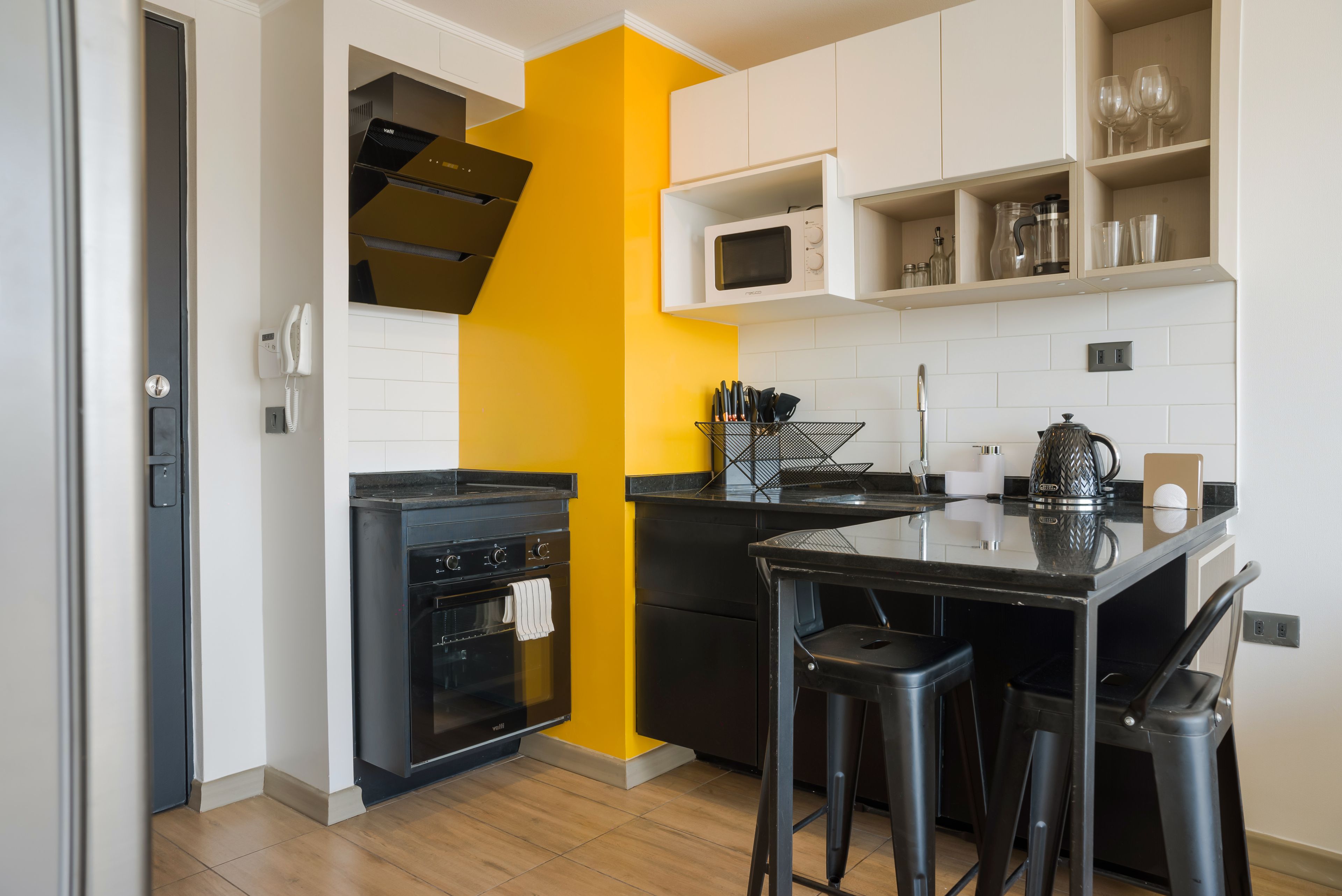 A compact kitchen with a microwave, oven, and a coffee machine.