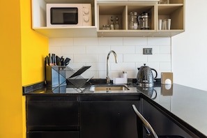 A modern kitchen with a black countertop, stainless steel sink, and a built-in microwave. - Modern Apartment in Ñuñoa for 3 Guest  (Ñuñoa)