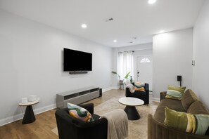 Een moderne woonkamer met een flatscreen televisie, een bank, een salontafel en een bijzettafeltje.
