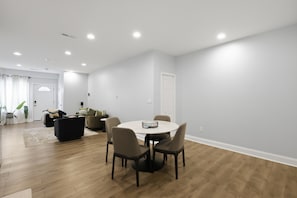 A modern living room with a round dining table, chairs, and a sofa. - Stylish 1bd Urban Haven Near Inner Harbor 1 Bedroom Apts (Baltimore)