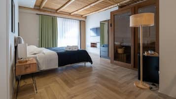 Un dormitorio moderno con cama, mesita de noche, lámpara y puerta corrediza de vidrio que da a un balcón.