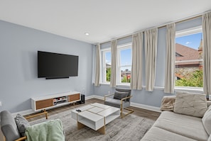 A modern living room with a flat-screen TV, a sofa, a coffee table, and a TV stand. - Expansive Urban Canvas In Baltimore 4 Bedroom Apts (Baltimore)