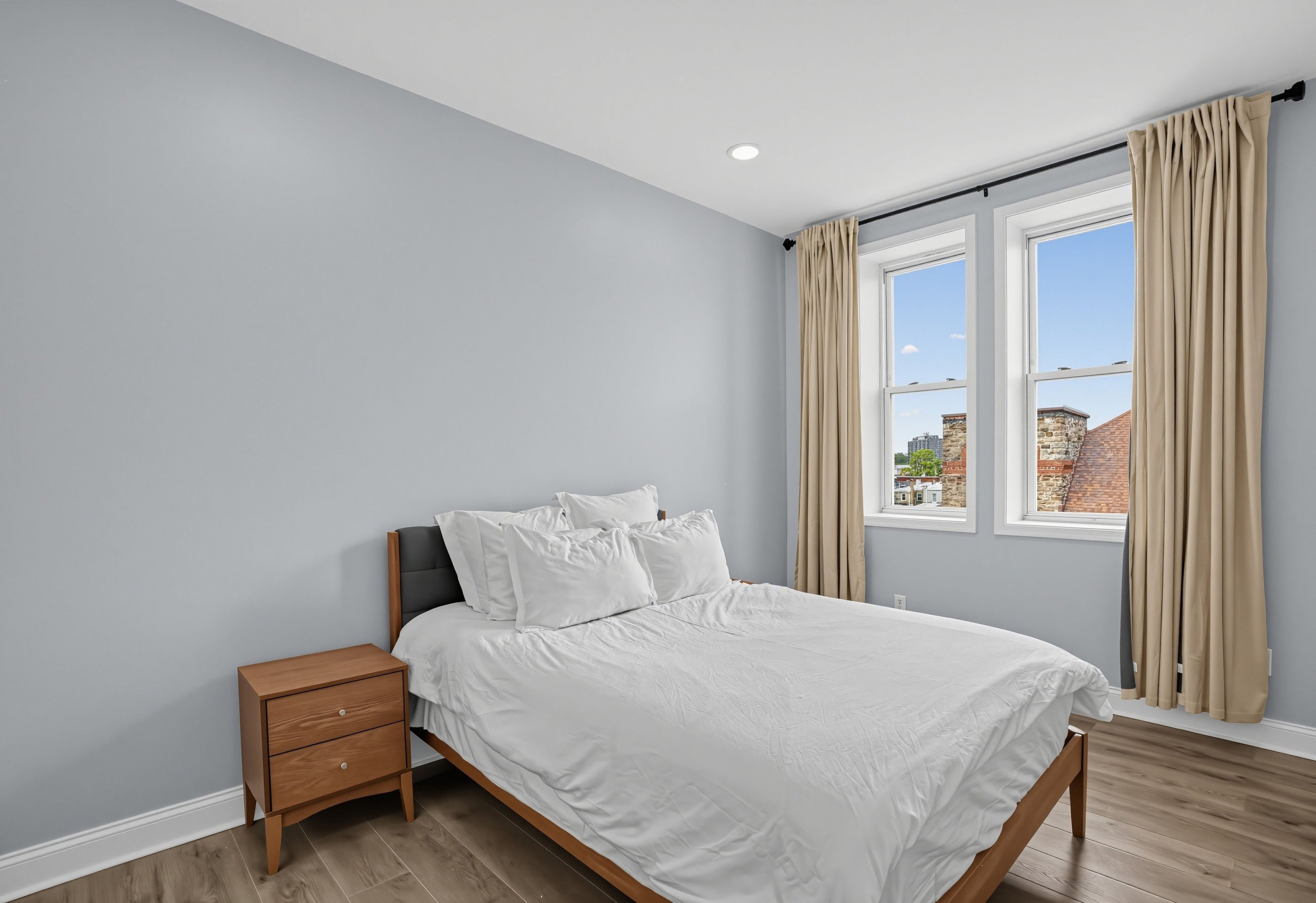 Une chambre à coucher avec un lit, une table de chevet et une fenêtre avec des rideaux.