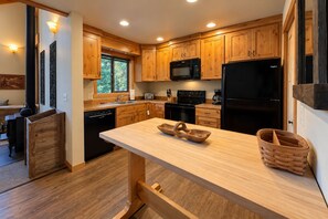 A modern kitchen with wooden cabinets, a black refrigerator, and a central island with a woven basket.