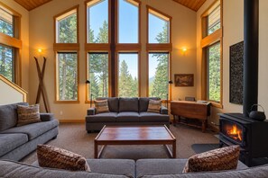 A spacious living room with a fireplace, large windows, and a cozy seating area.