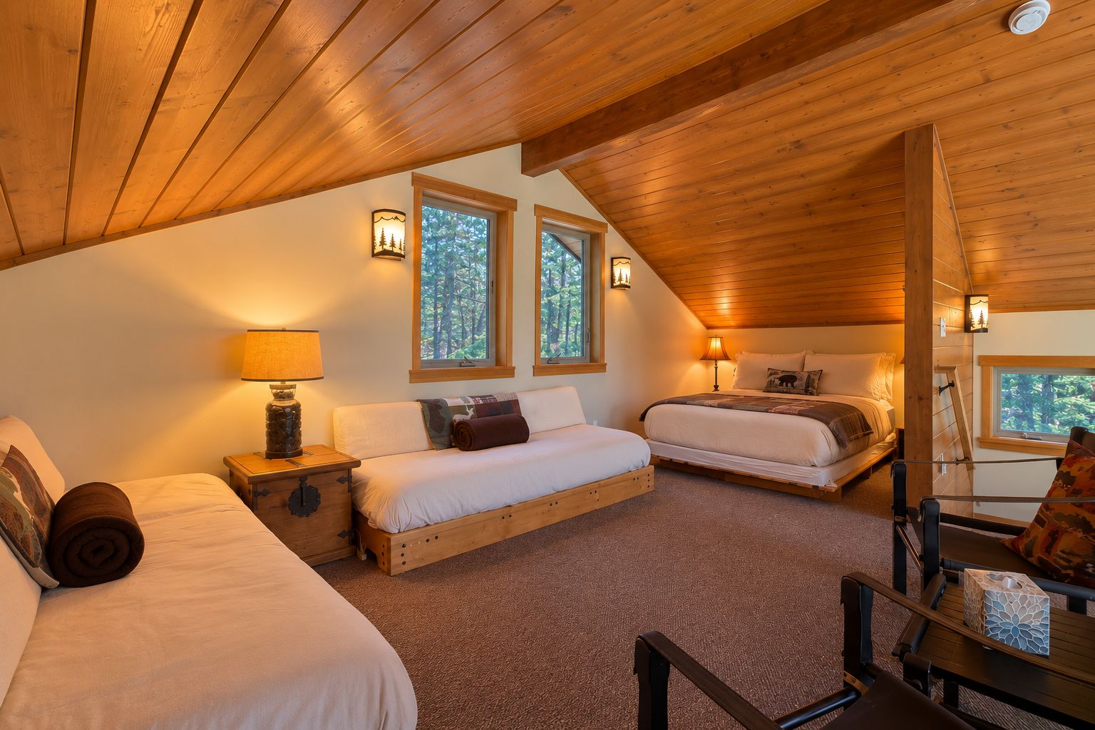 Ein gemütliches Schlafzimmer mit zwei Betten, Holzboden und Fenstern mit Blick auf einen Wald.